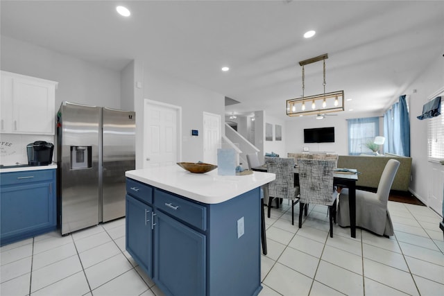 kitchen with stainless steel fridge, a center island, white cabinets, and blue cabinets