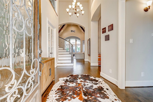 entrance foyer featuring ceiling fan with notable chandelier, a high ceiling, and dark hardwood / wood-style floors