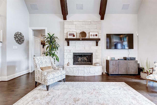 living room featuring dark hardwood / wood-style floors, beam ceiling, and a stone fireplace