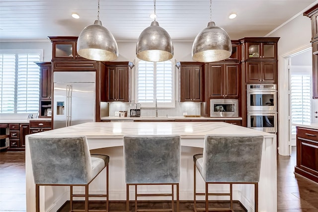 kitchen with built in appliances, a center island, plenty of natural light, and hanging light fixtures