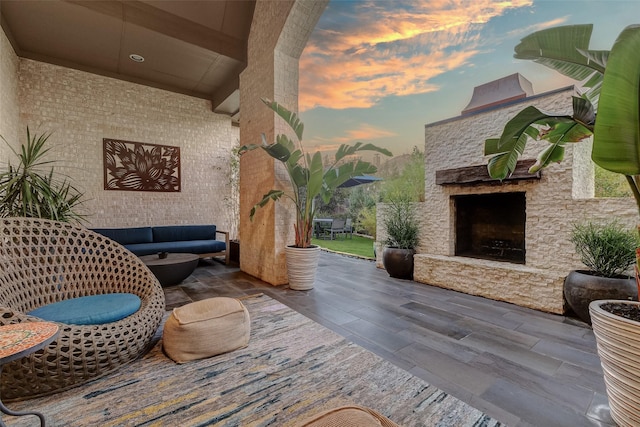 patio terrace at dusk featuring an outdoor stone fireplace