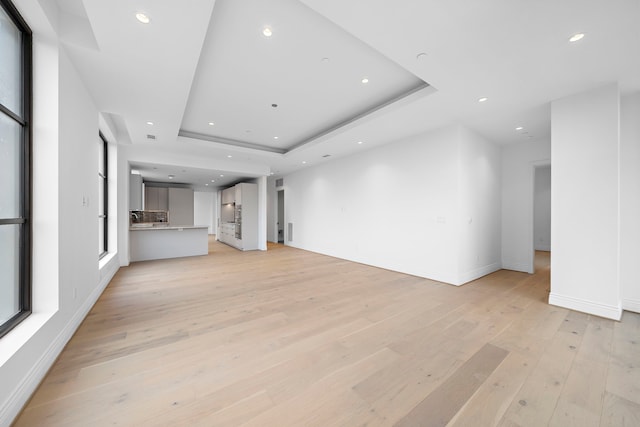 unfurnished living room featuring light hardwood / wood-style flooring and a raised ceiling