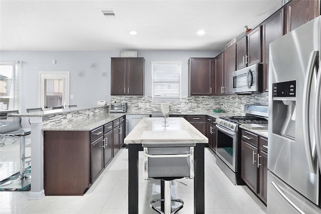 kitchen with a kitchen breakfast bar, a kitchen island, dark brown cabinets, and stainless steel appliances