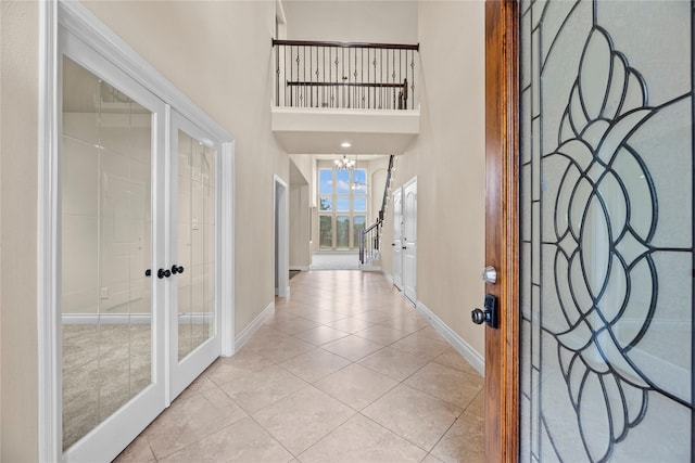 tiled entrance foyer featuring a chandelier, a high ceiling, and french doors