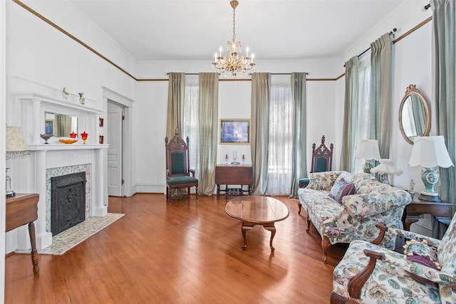 living room with a high end fireplace, ornamental molding, hardwood / wood-style flooring, and a notable chandelier