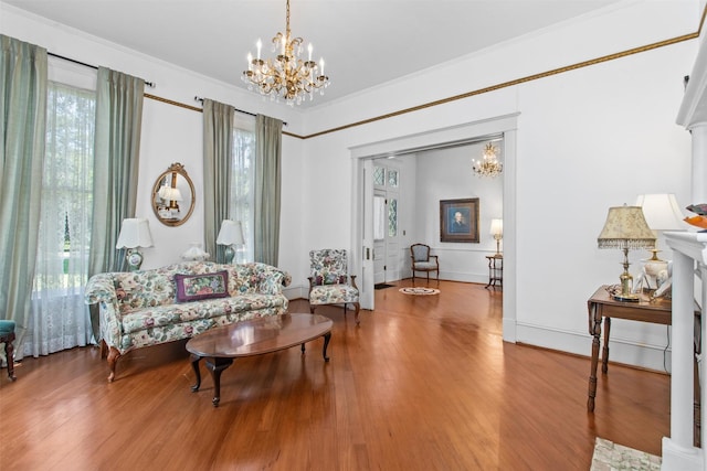 sitting room with wood-type flooring, crown molding, a wealth of natural light, and a notable chandelier