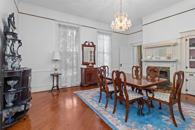 dining space with a brick fireplace, crown molding, wood-type flooring, and a notable chandelier