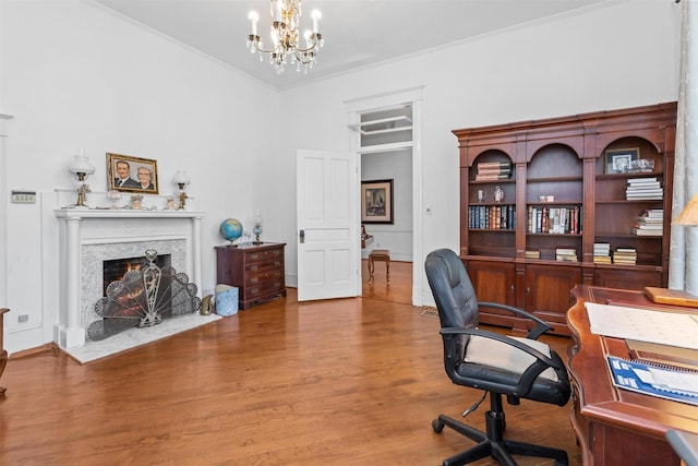 office space with crown molding, a fireplace, an inviting chandelier, and hardwood / wood-style flooring