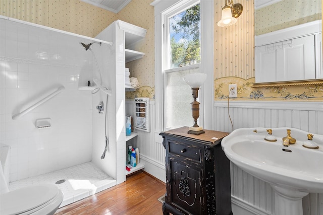 bathroom featuring sink, toilet, hardwood / wood-style floors, and tiled shower