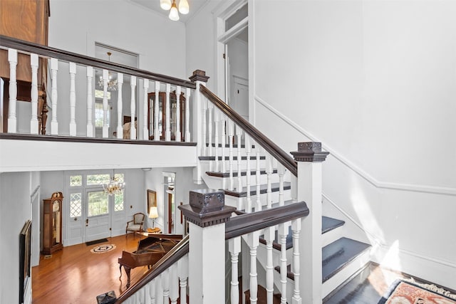 stairs featuring a chandelier, a high ceiling, and wood-type flooring