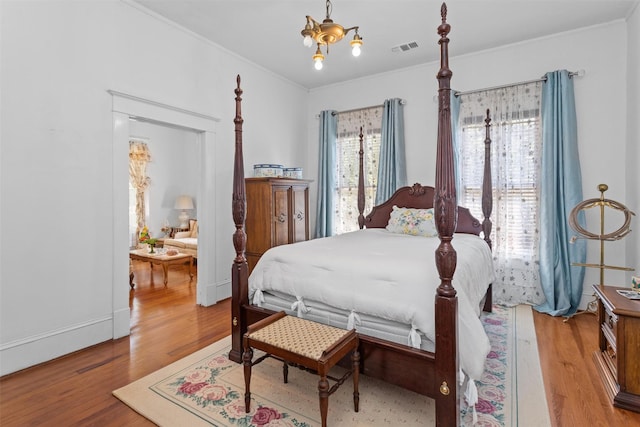 bedroom featuring a chandelier, hardwood / wood-style flooring, and crown molding