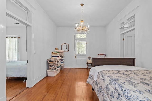 bedroom featuring crown molding, hardwood / wood-style floors, and an inviting chandelier