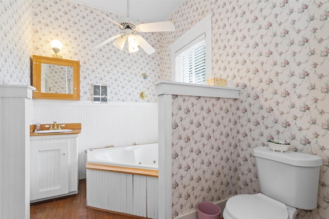 bathroom with a bathing tub, ceiling fan, toilet, vanity, and hardwood / wood-style flooring