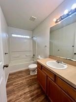 full bathroom featuring hardwood / wood-style flooring, vanity, toilet, and bathing tub / shower combination