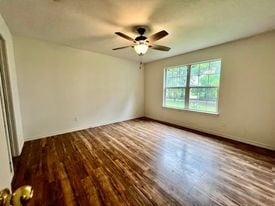 unfurnished room with dark hardwood / wood-style floors and ceiling fan