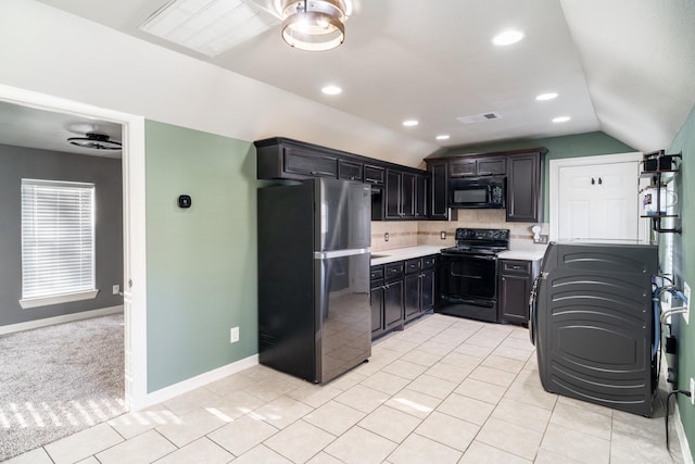 kitchen with black appliances, decorative backsplash, light tile patterned flooring, and lofted ceiling