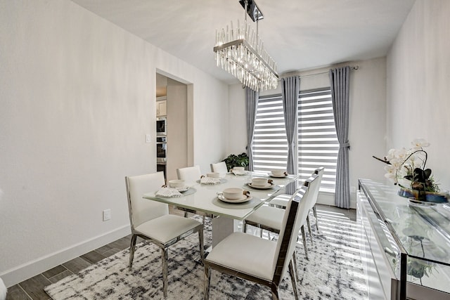 dining area with dark wood-type flooring, baseboards, and an inviting chandelier