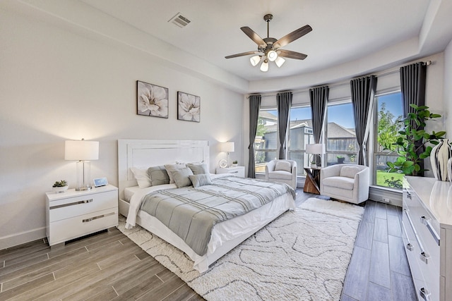 bedroom with ceiling fan, light wood-style flooring, visible vents, and baseboards