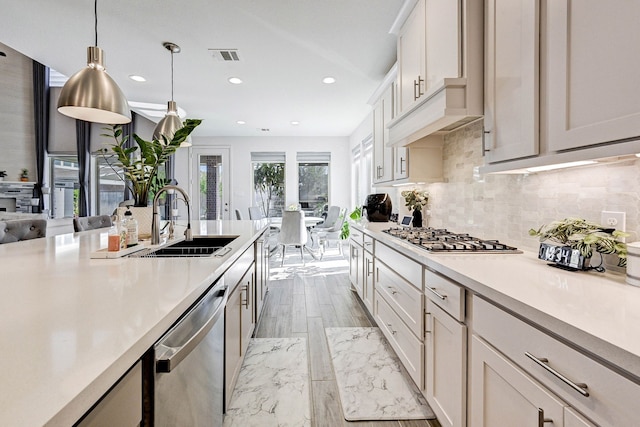 kitchen with a sink, visible vents, light countertops, appliances with stainless steel finishes, and decorative light fixtures