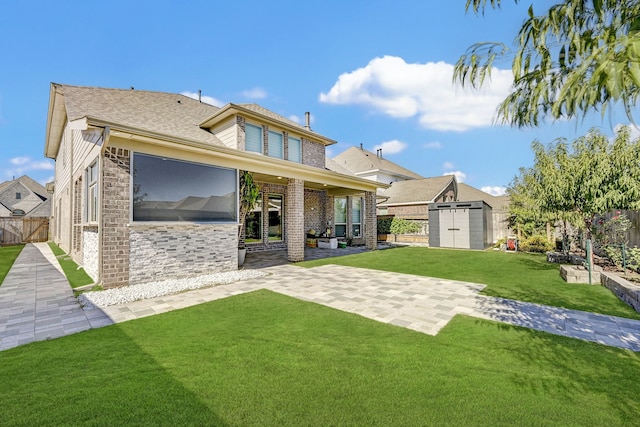 rear view of property featuring an outbuilding, a storage shed, fence, a lawn, and a patio area