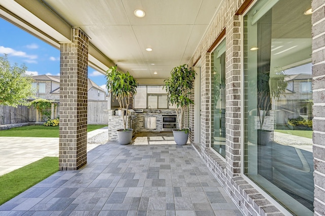 view of patio with fence, an outdoor kitchen, and a sink