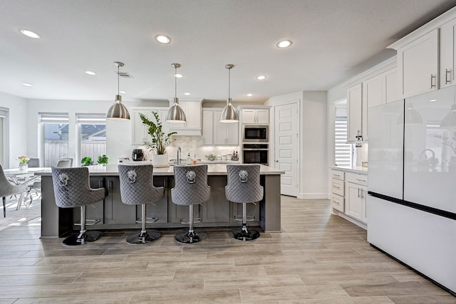 kitchen featuring light countertops, freestanding refrigerator, white cabinetry, stainless steel oven, and built in microwave