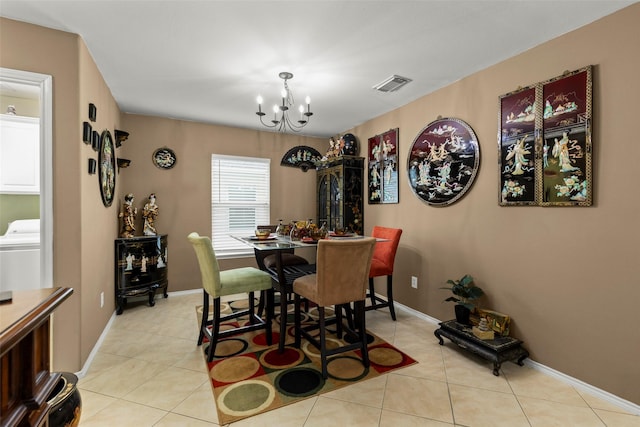 dining room featuring washer / dryer, a notable chandelier, and light tile patterned floors