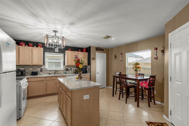 kitchen featuring white appliances, a center island, light stone countertops, light brown cabinets, and sink