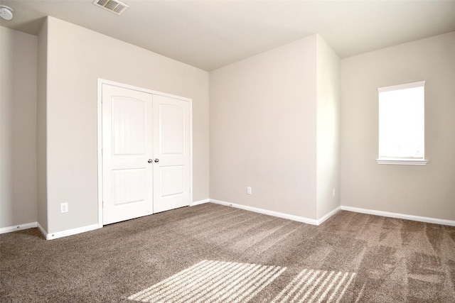 unfurnished bedroom featuring a closet and dark colored carpet