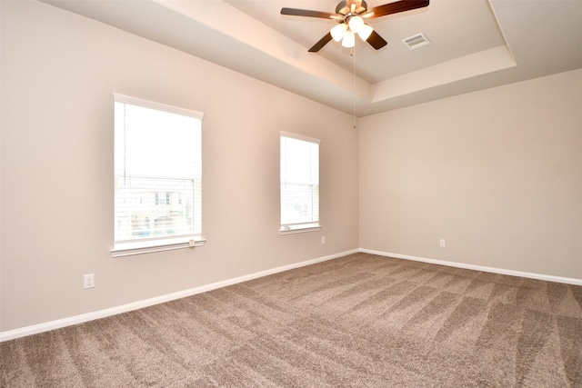 unfurnished room with a tray ceiling, ceiling fan, and carpet floors