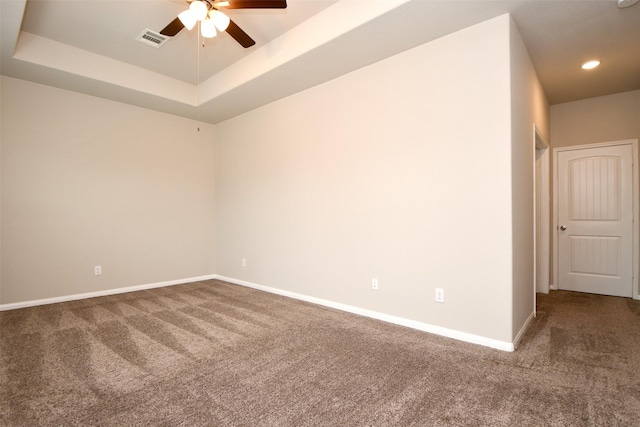 carpeted spare room with a raised ceiling and ceiling fan