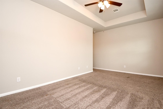 carpeted empty room featuring a tray ceiling and ceiling fan