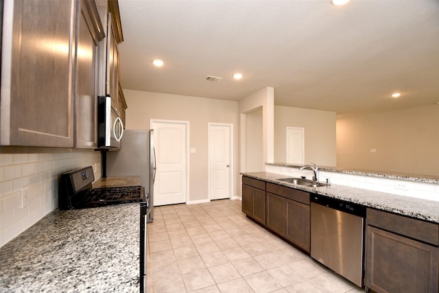 kitchen featuring decorative backsplash, light stone counters, sink, and appliances with stainless steel finishes