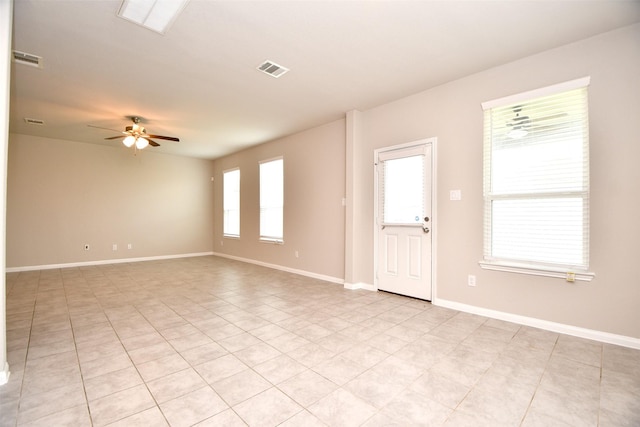 spare room with ceiling fan, a healthy amount of sunlight, and light tile patterned floors