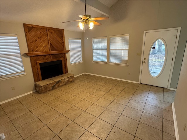 unfurnished living room featuring vaulted ceiling with beams, ceiling fan, light tile patterned floors, and a stone fireplace