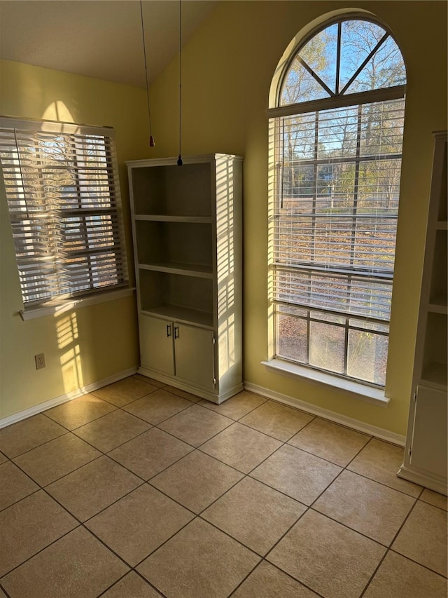 unfurnished dining area with lofted ceiling and light tile patterned floors