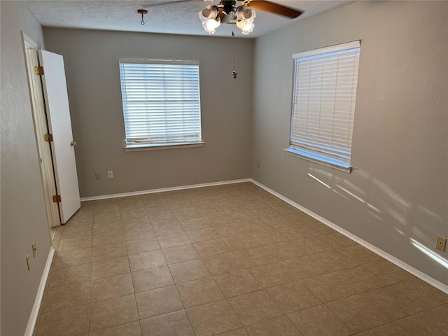 tiled spare room featuring a textured ceiling and ceiling fan