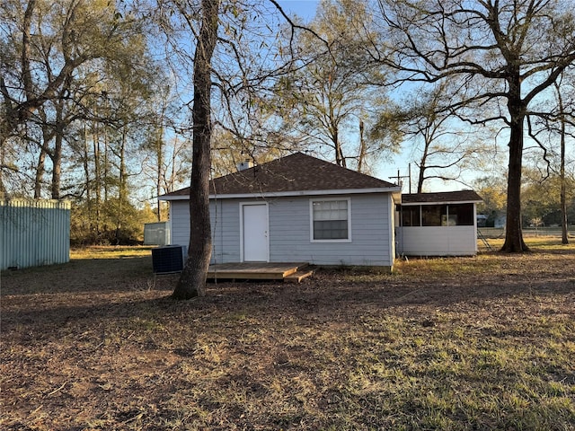 rear view of house with central air condition unit and a sunroom