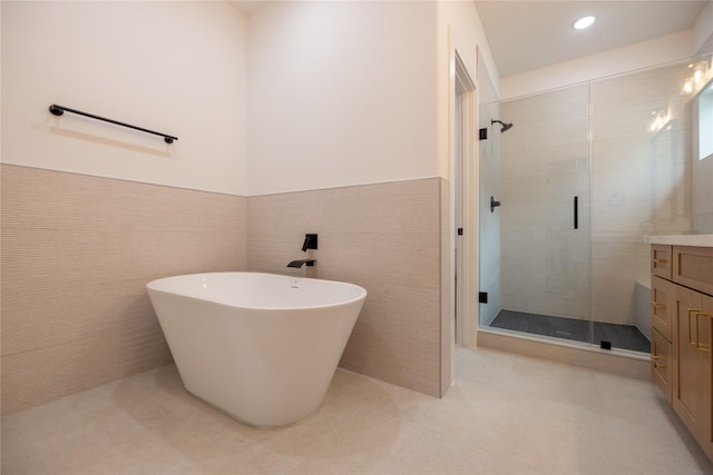 bathroom with tile patterned floors, vanity, tile walls, and independent shower and bath