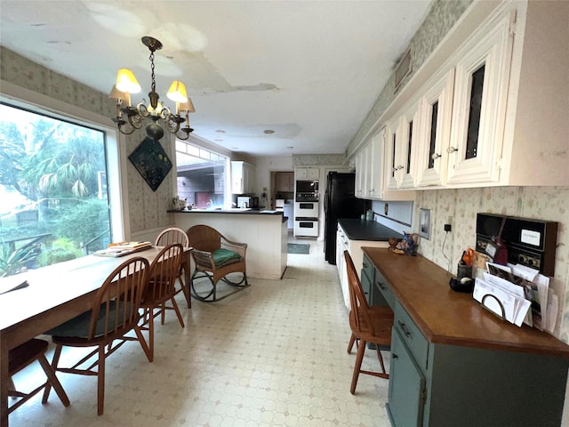 dining room with a chandelier, wallpapered walls, and light floors