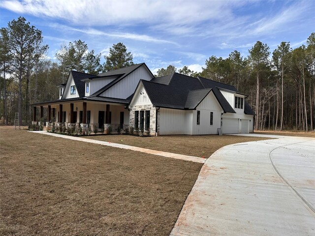 modern inspired farmhouse with a front yard, covered porch, and a garage