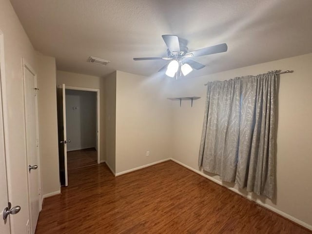 empty room with ceiling fan and dark hardwood / wood-style flooring