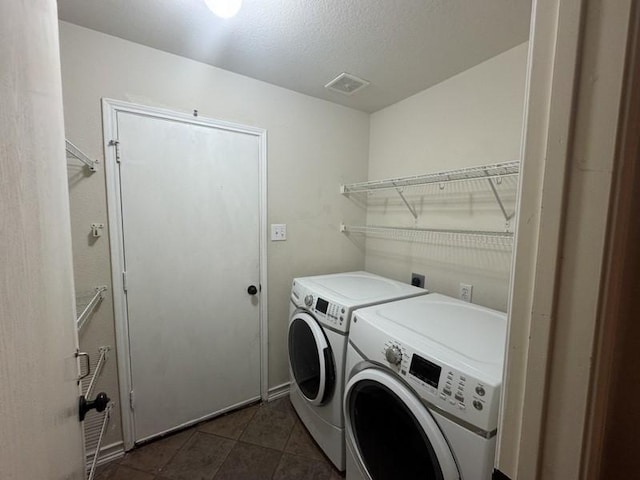 washroom featuring washer and clothes dryer, dark tile patterned floors, and a textured ceiling