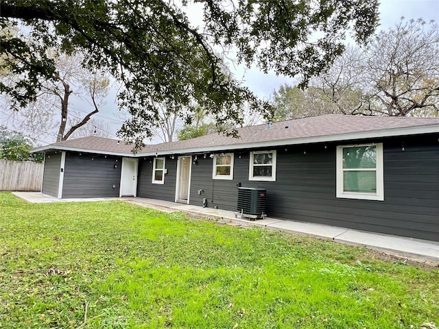 rear view of property with a patio area, cooling unit, and a yard