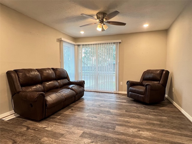 living room with ceiling fan, dark hardwood / wood-style floors, and a textured ceiling