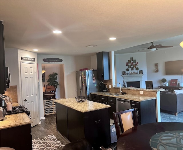 kitchen with appliances with stainless steel finishes, a center island, dark wood-type flooring, sink, and light stone counters