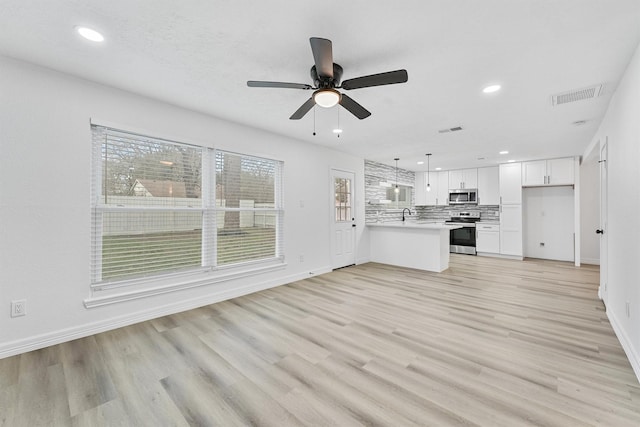 unfurnished living room featuring light hardwood / wood-style floors, ceiling fan, and sink