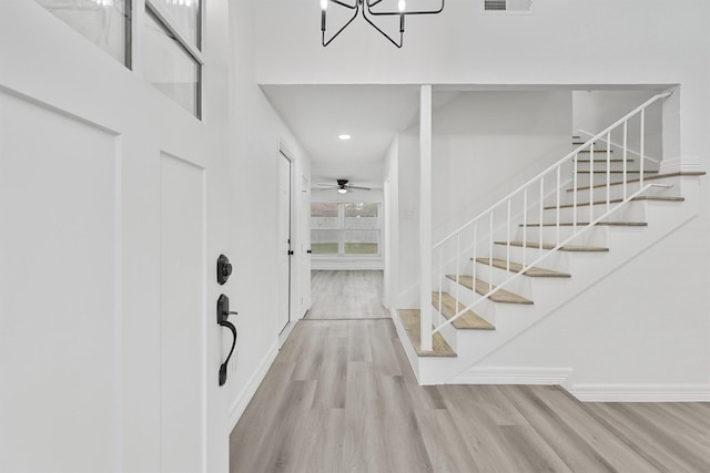 entrance foyer featuring ceiling fan with notable chandelier and light wood-type flooring