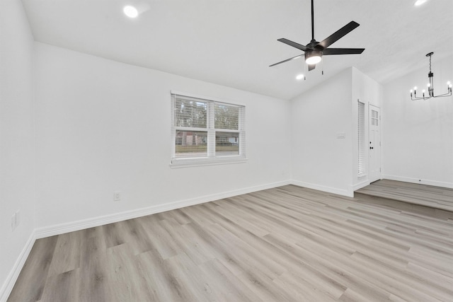 unfurnished room with ceiling fan with notable chandelier, light hardwood / wood-style floors, and lofted ceiling