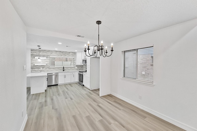 kitchen with tasteful backsplash, stainless steel appliances, light hardwood / wood-style flooring, white cabinetry, and hanging light fixtures